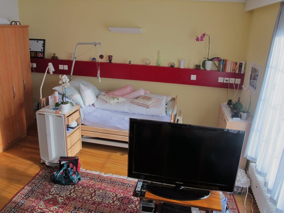 Ein Zimmer im Hospiz mit einem Bett, einem Fernseher und zwei Schränken