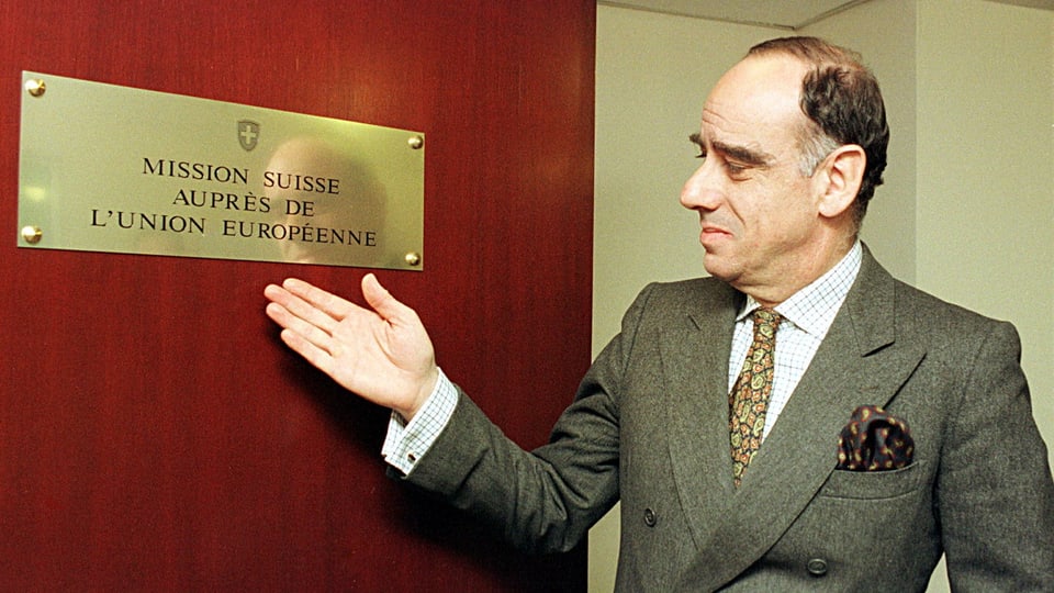 Alexis Lautenberg zeigt auf das Schild an der Tür der Schweizer Mission in Brüssel im Jahr 1998.