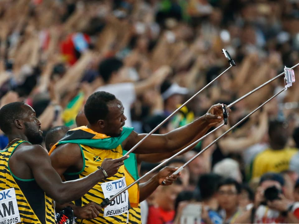 Usain Bolt und Co. lächeln in Handkameras.