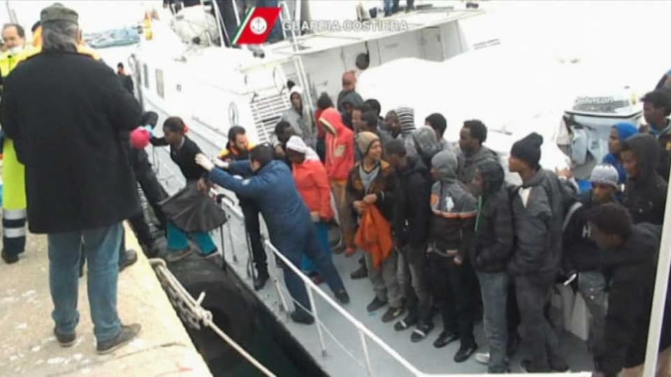 Afrikanischen Flüchtlingen wird im Hafen aus dem Boot geholfen.