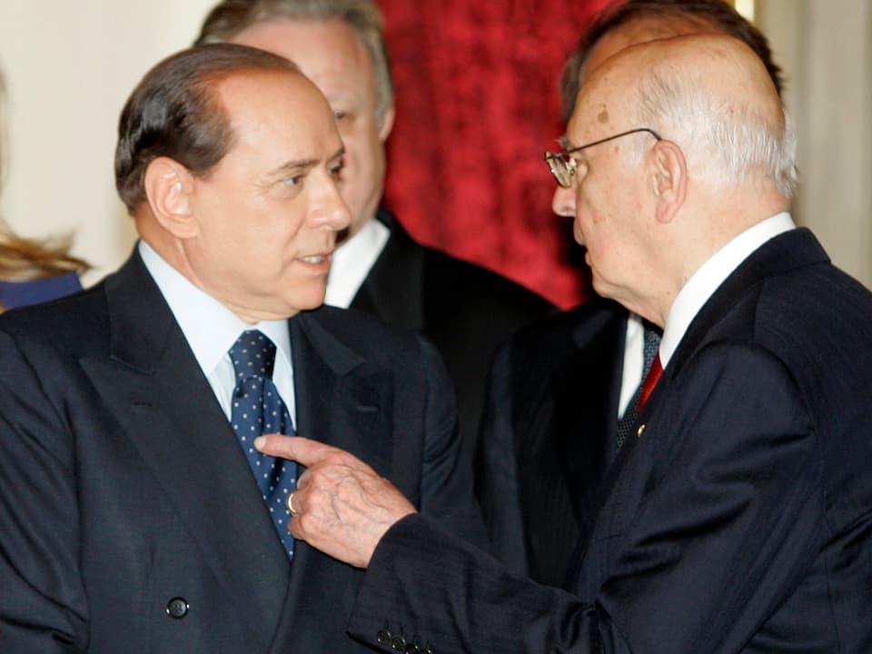 Napolitano spricht mit Silvio Berlusconi und zeigt mit dem Finger auf ihn.