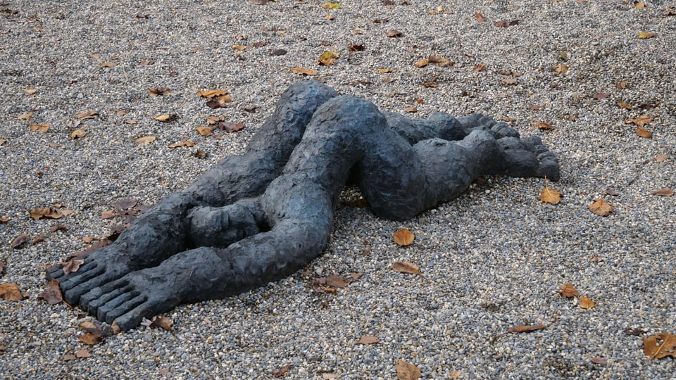Eine Figur aus Stein liegt am Boden.