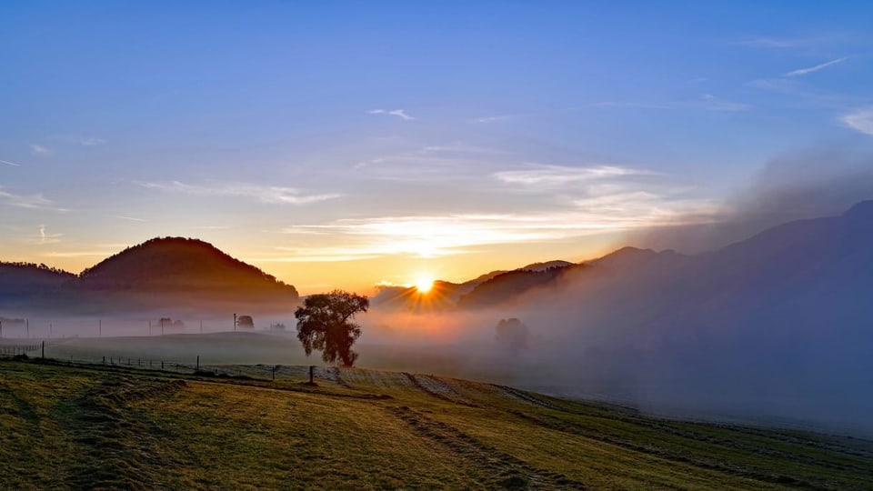 Die Sonne löst am Morgen den Nebel über Bretzwil auf.