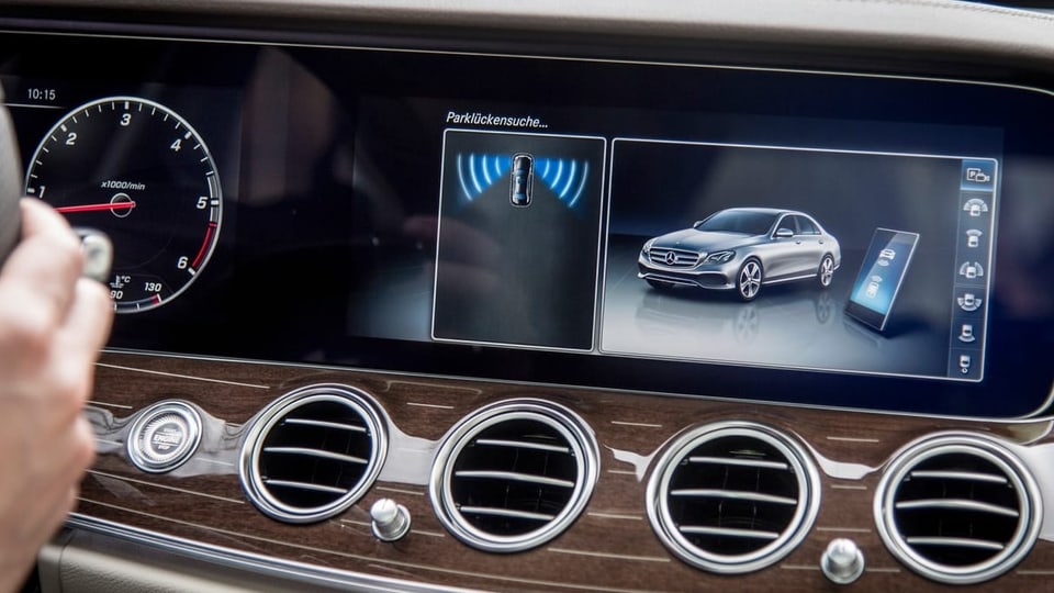 Ein Monitor im Innenraum eines Fahrzeugs, darauf das Fahrzeug von Aussen.