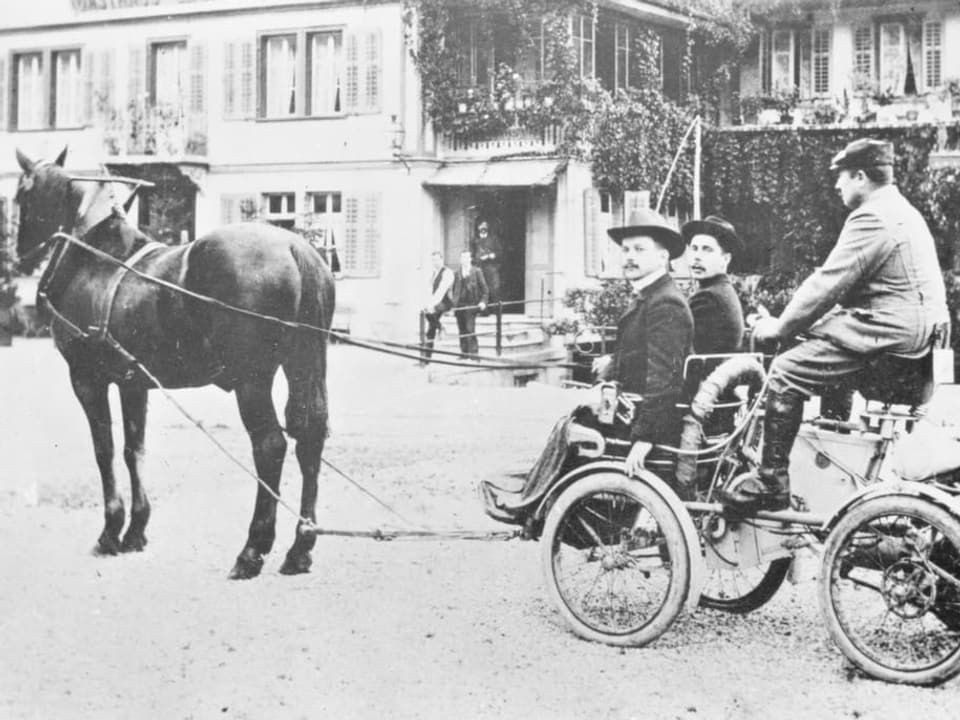 Aufnahme aus etwa 1910, auf der ein Auto von einem Pferd gezogen wird.