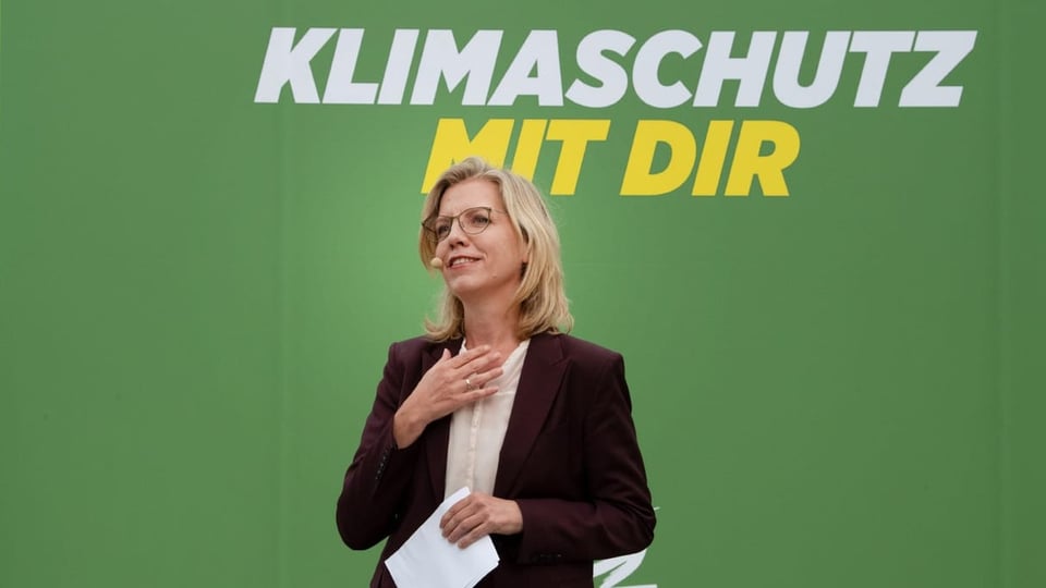 Leonore Gewessler steht vor einer Wand mit der Aufschrift «Klimaschutz mit dir»