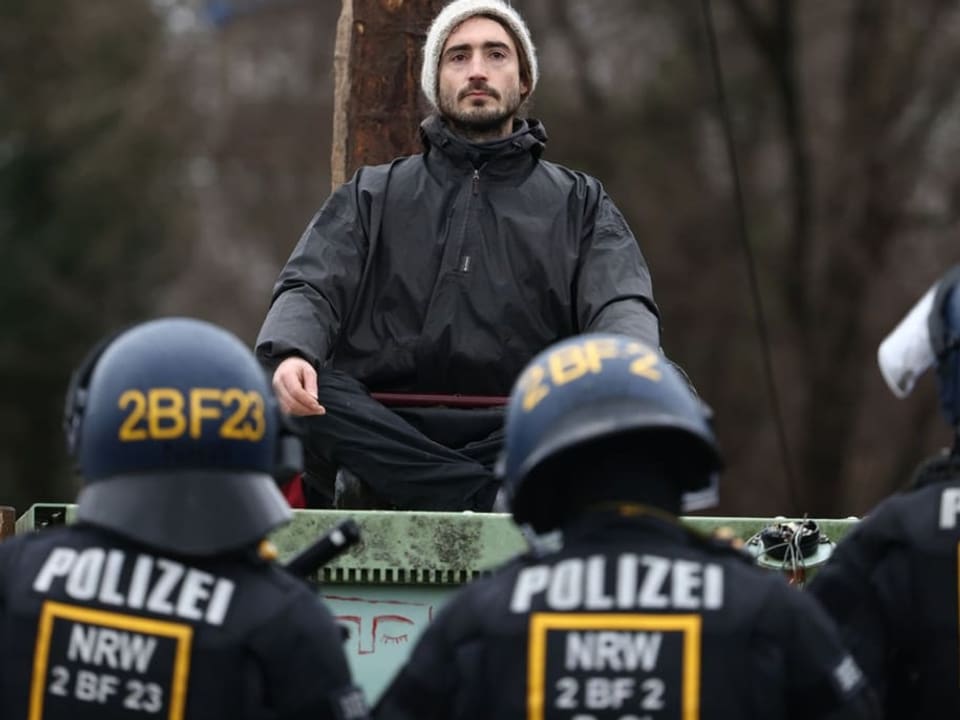 Sitzender junger Mann mit Polizisten im Vordergrund