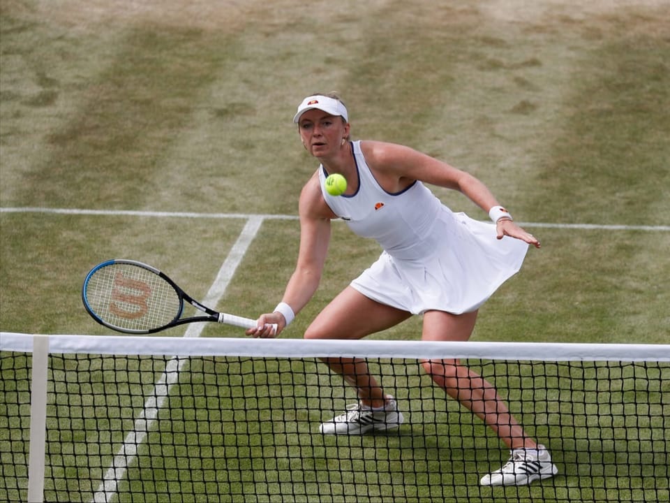 Eine Tennisspielerin ganz in Weiss spielt in Wimbledon.