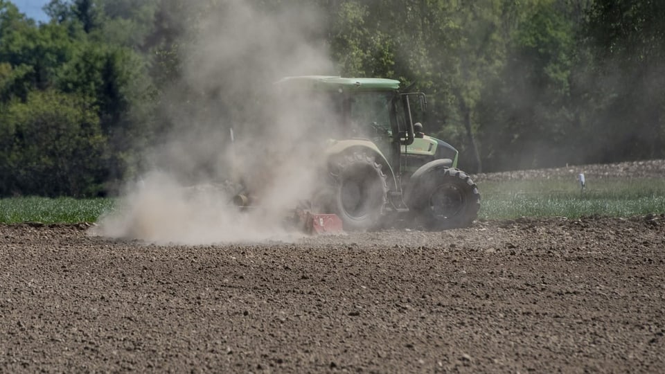 Ein Traktor, der auf einem staubigen Feld fährt