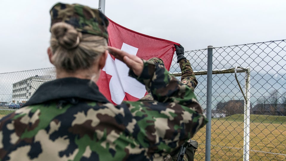 Soldatin salutiert vor Schweizer Flagge