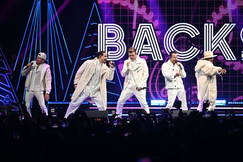 Backstreet Boys in weissen Outfits auf der Bühne während eines Konzerts.