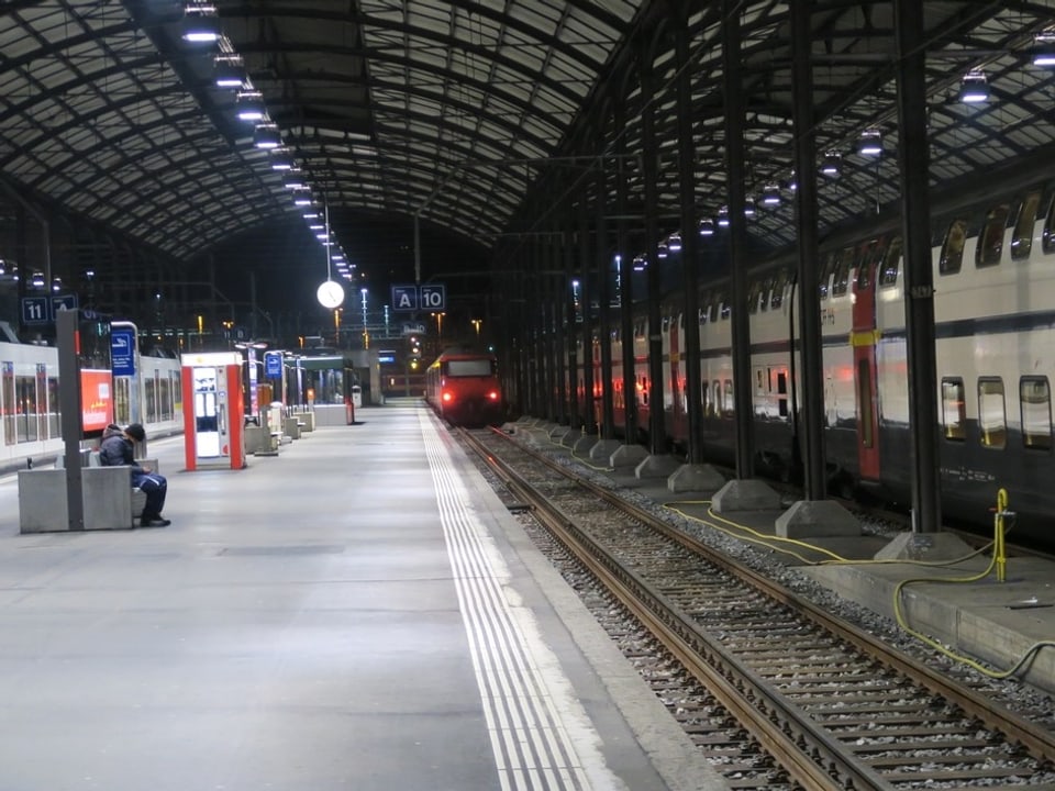Ein fast leeres Perron und der Zug, der aus dem Bahnhof fährt.