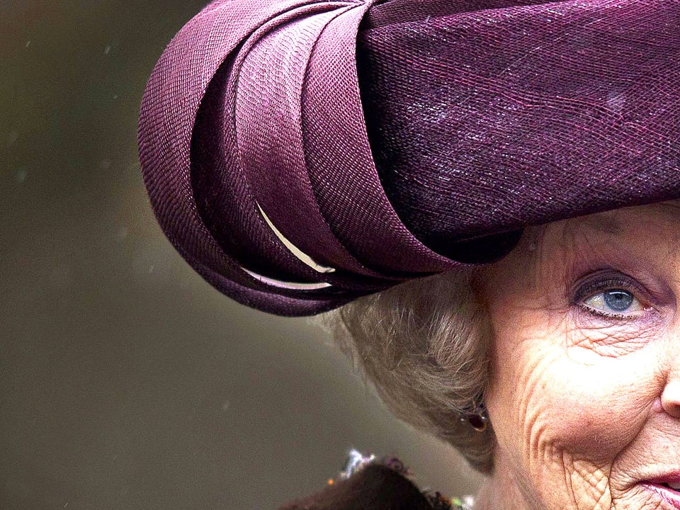 Portrait der Hälfte des Gesichts der Königin Beatrix von Niederlanden. Ihr Blick ist kühl und durchdringend zugleich.