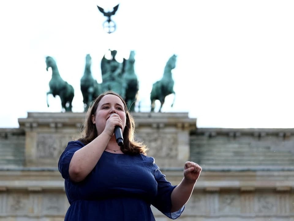 Frau singt vor dem Brandenburger Tor in Berlin.