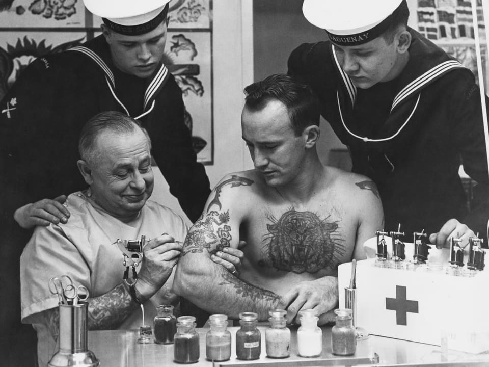 Ein Tatowierer, Forbes A. Hendry, finalisiert ein Tattoo auf dem Ex-Navy Mann Joe Williams.