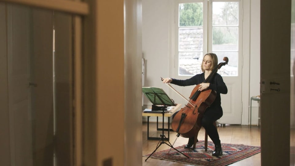 Eine Frau spielt auf einem Teppich Cello.