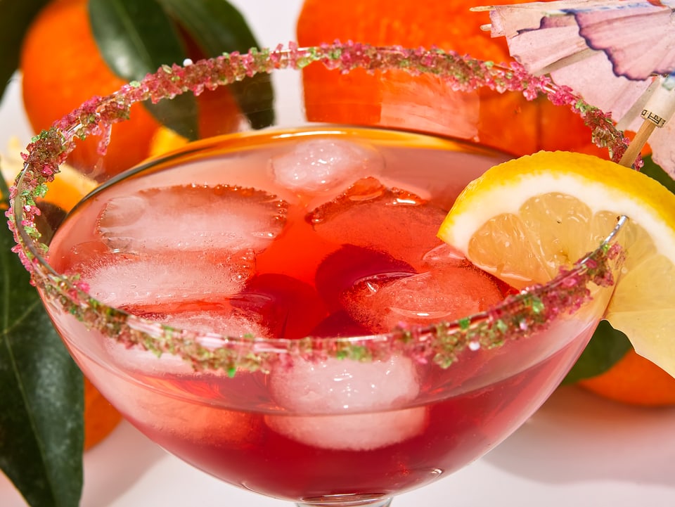 Roter Aperitiv-Drink in einem Glas mit Eiswürfeln und Zitrone
