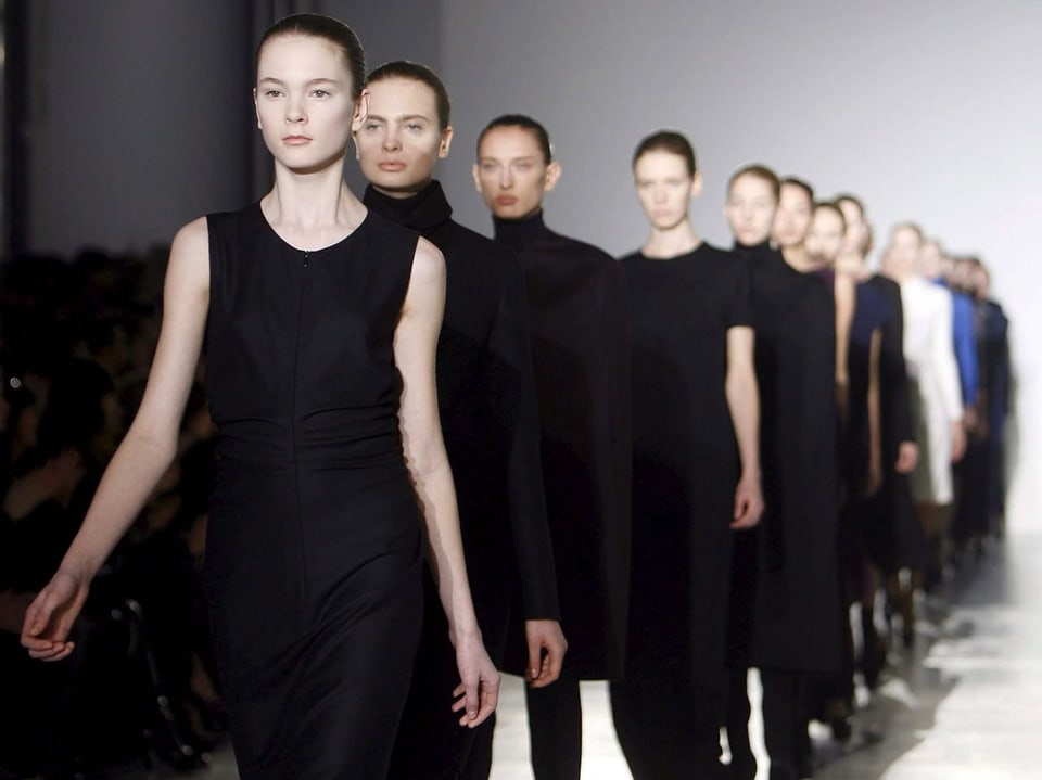 Mehrere junge Models gehen schwarz gekleidet über den Laufsteg.