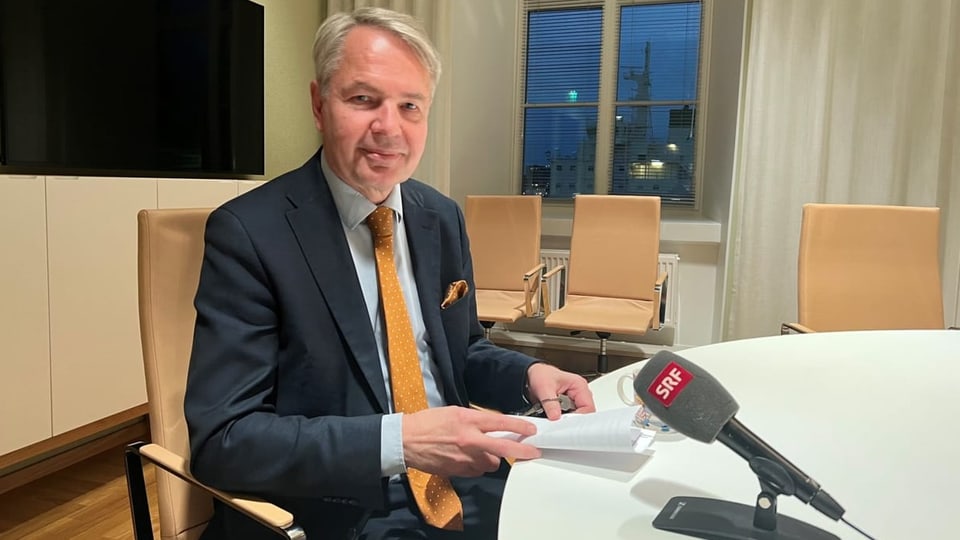 Haavisto an einem Tisch, vor ihm ein Mikrofon mit dem SRF-Logo.