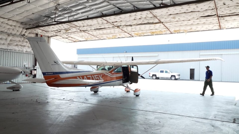 Mann geht zu kleinem Flugzeug in Hangar