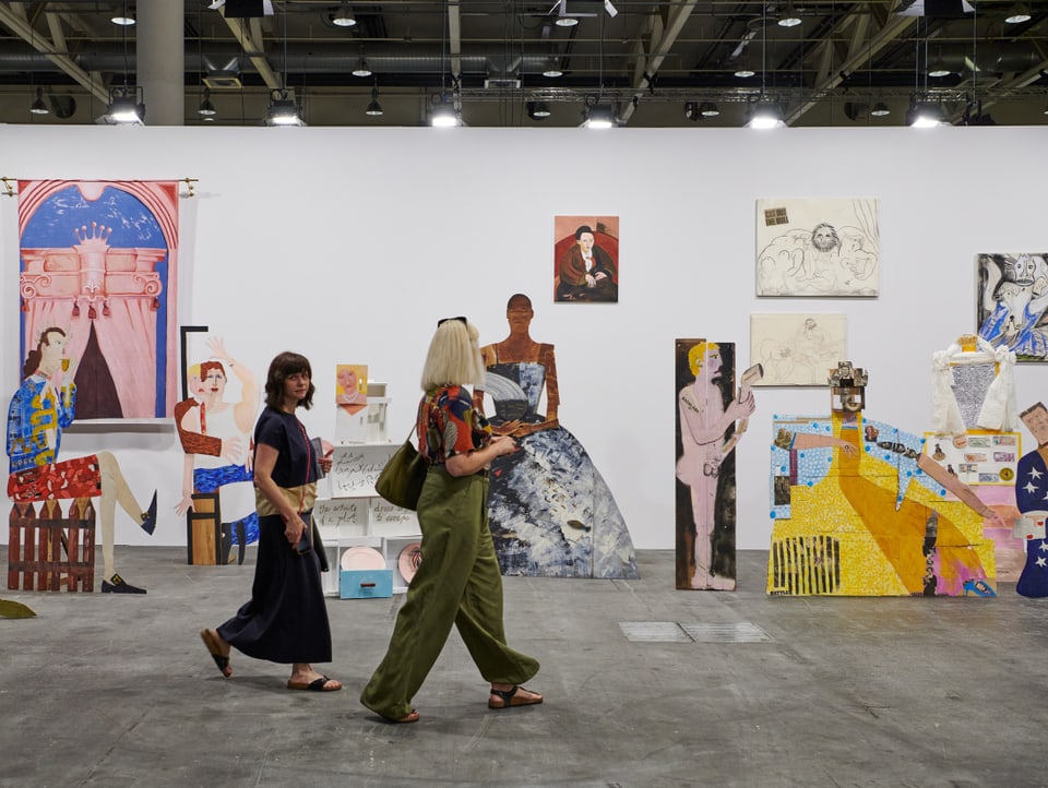 Zwei Besucherinnen laufen an bunten Kunstwerken der Art Basel vorbei, 