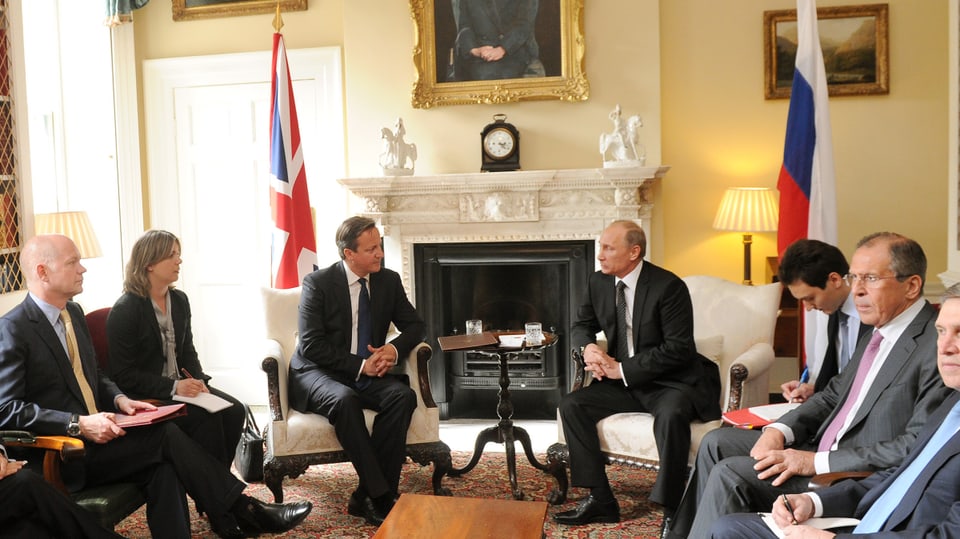 Putin und Cameron sitzend vor einem Kamin.
