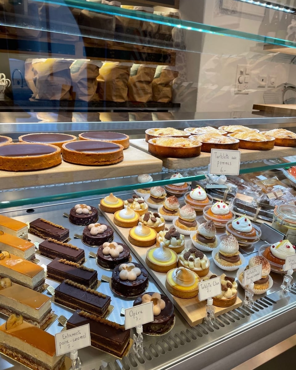 Auslage von verschiedenen Kuchen und Törtchen: links dunkle Schnitten, in der Mitte runde Tartelette, rechts ein Mousse.