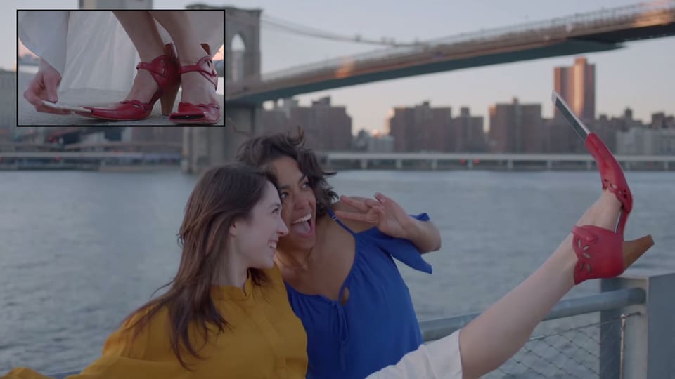 Zwei junge Frauen machen ein Selfie, die eine der beiden streckt dazu ihr Bein in die Luft, in ihren Schuh hat sie vorne ein Smartphone geschoben.