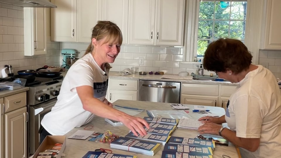 Zwei Frauen bündeln Flyer in einer Küche.