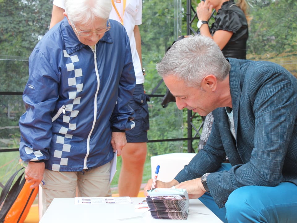Dani Fohrler unterschreibt für eine Besucherin eine Autogrammkarte.