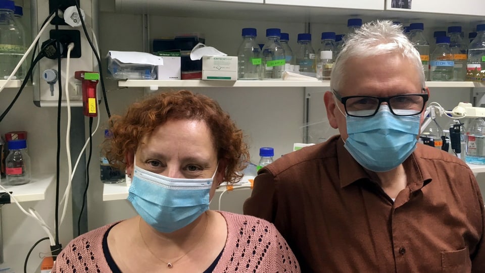Eine Frau und ein Mann in einem Labor. Sie tragen Schutzmasken