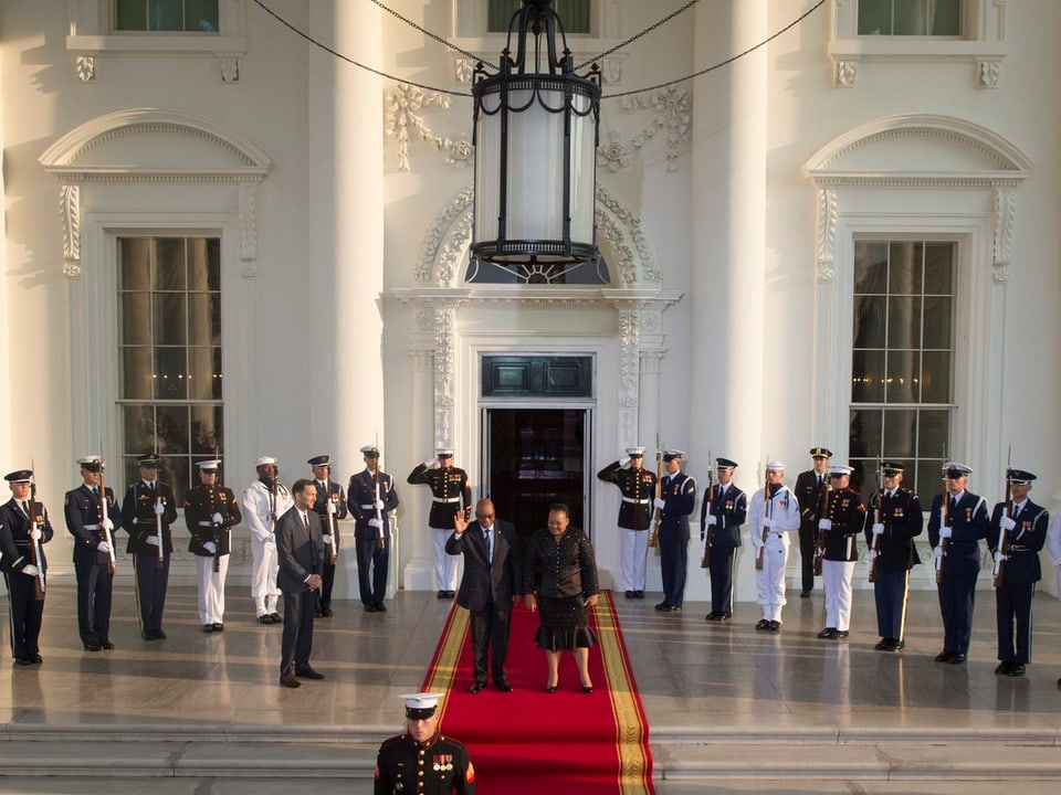 Südafrikas Präsident Zuma tritt mit einer seiner Ehefrauen auf dem roten Teppich aus dem Weissen Haus, Ehrengarden stehen bereit. 