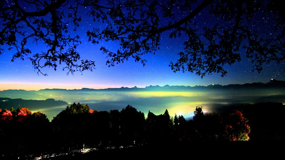 Blick ins Tal bei Nacht, dahinter glühen die Berge