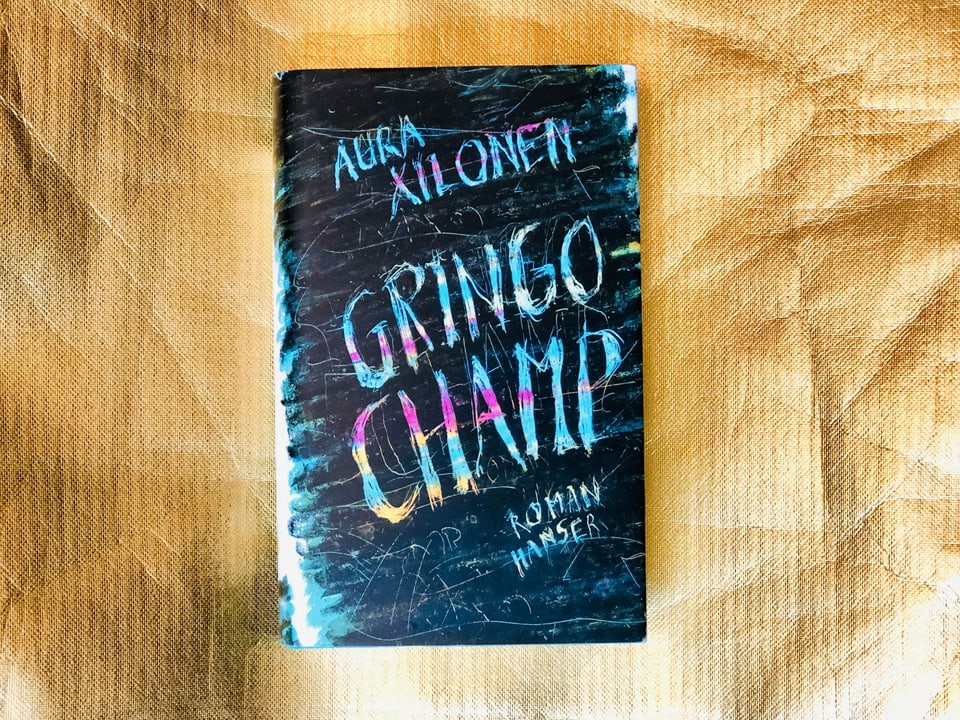 Der Roman «Gringo Champ» von Aura Xilonen vor goldigem Hintergrund