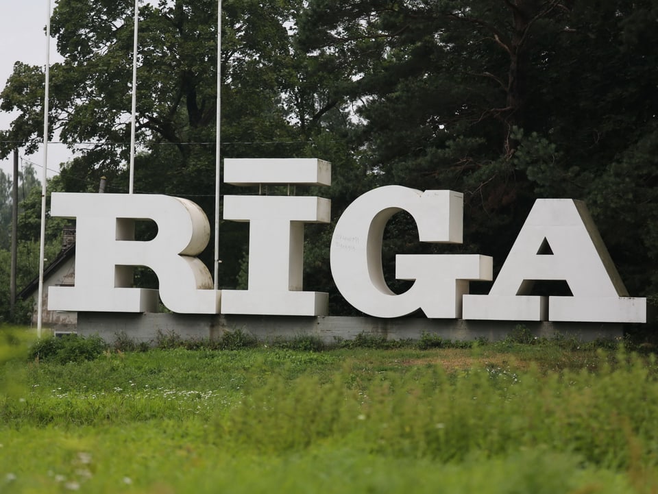 Auf einer Wiese bilden grosse, weisse Buchstaben das Wort «Riga».