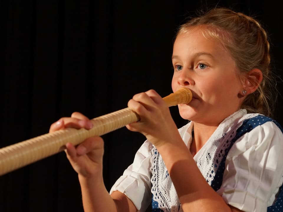 Mädchen spielt Alphorn.
