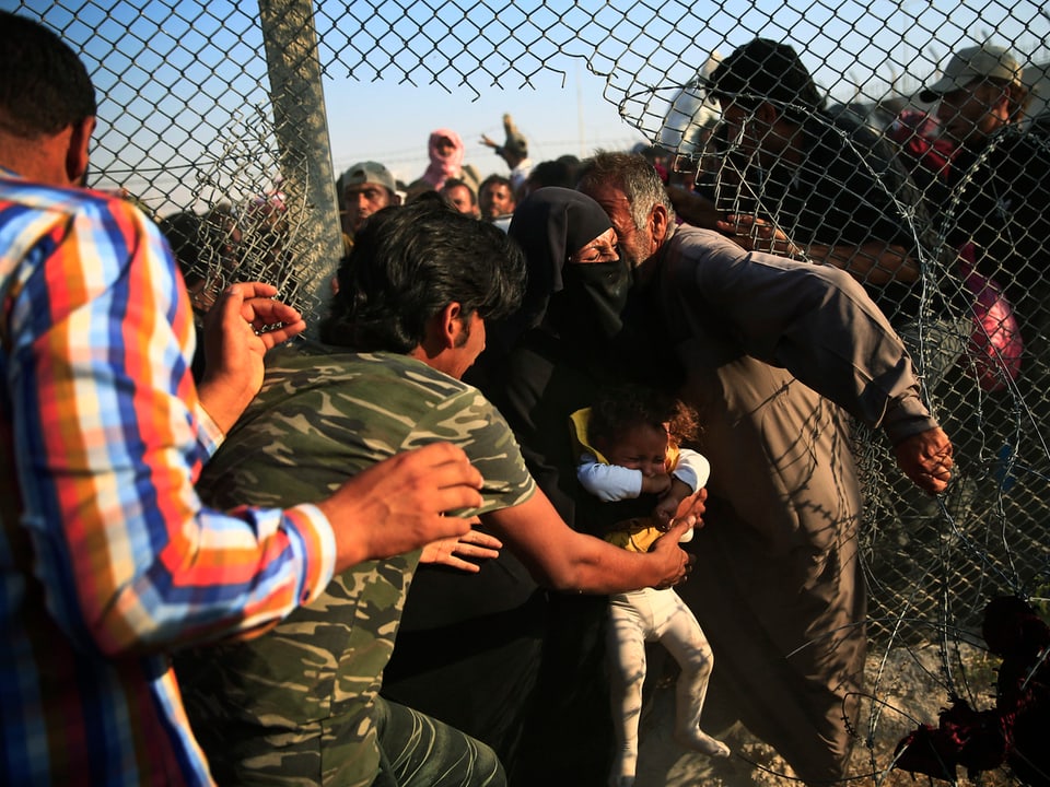 Flüchtlinge passieren den Grenzzaun zur Türkei.