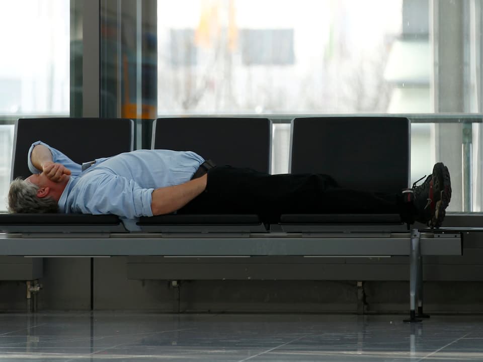 Ein Passagier schläft auf einer Bank. 