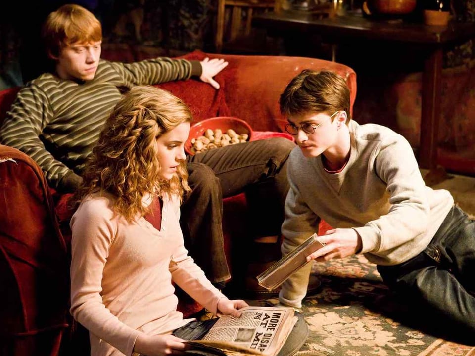 Filmausschnitt Harry Potter: Die drei Hauptdarsteller sitzen auf Sofa und am Boden zusammen
