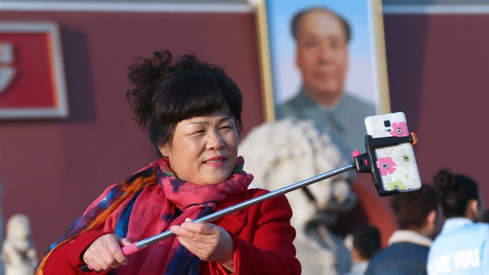 Eine Frau macht ein Selfie von sich und einem Bild von Mao Zedong.