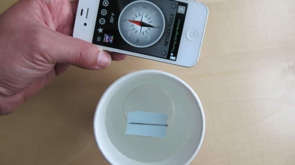 Kompass-Experiment: Wasserschale mit einem Papier drin, Handy mit Kompass als Kontrolle