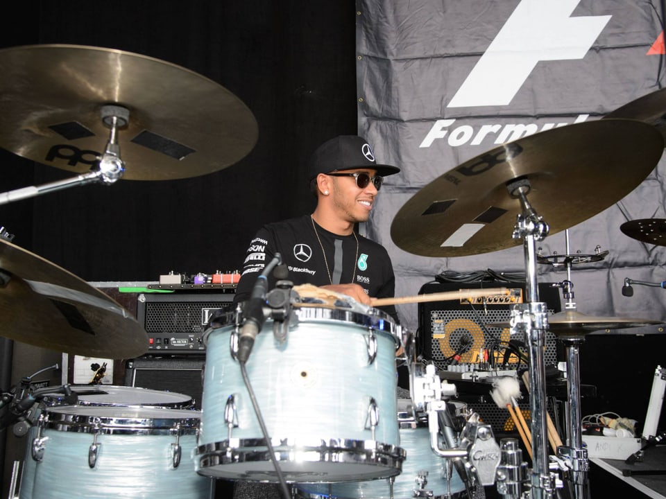 Lewis Hamilton sitzt am Schlagzeug und spielt.