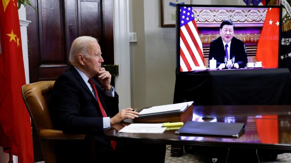 Joe Biden am Schreibtisch, neben ihm auf einem Bildschirm ist Xi Jinping zu sehen.