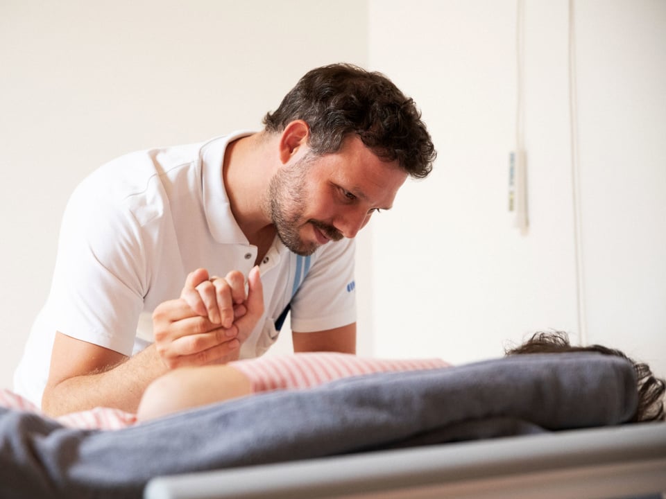 Christof Meiser hält die Hand einer Frau, die auf dem Bett liegt