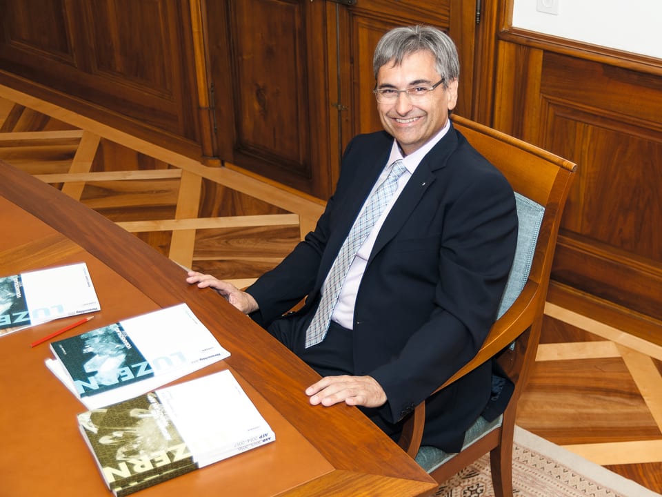 Guido Graf sitzt an einem Tisch mit der Staatsrechnung auf der Tisch.