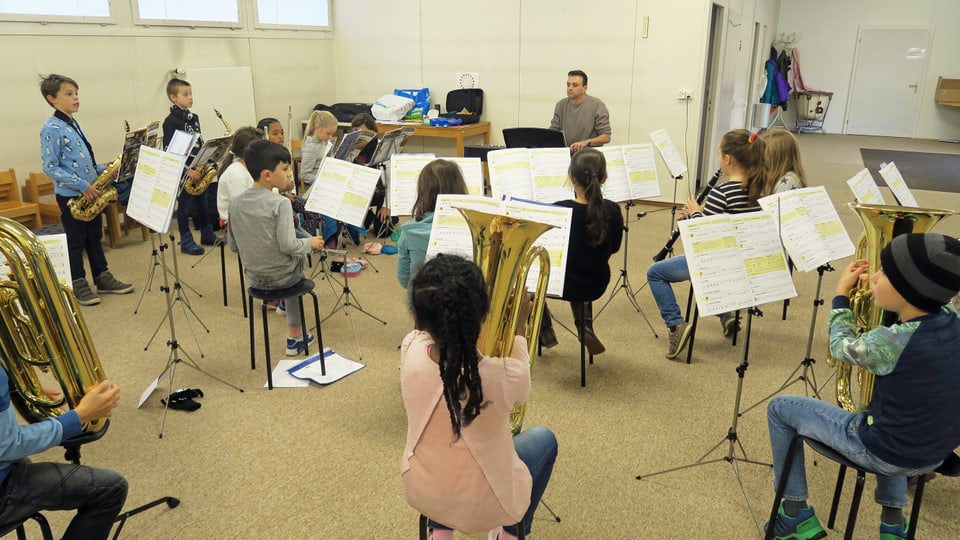 Eine Schulklasse spielt auf verschiedenen Musikinstrumenten. 