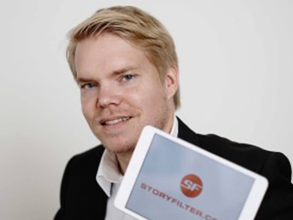 Porträt von Bernhard Brechbühl, er hat ein Tablet in der Hand, dass das Logo "Storyfilter.com" zeigt.