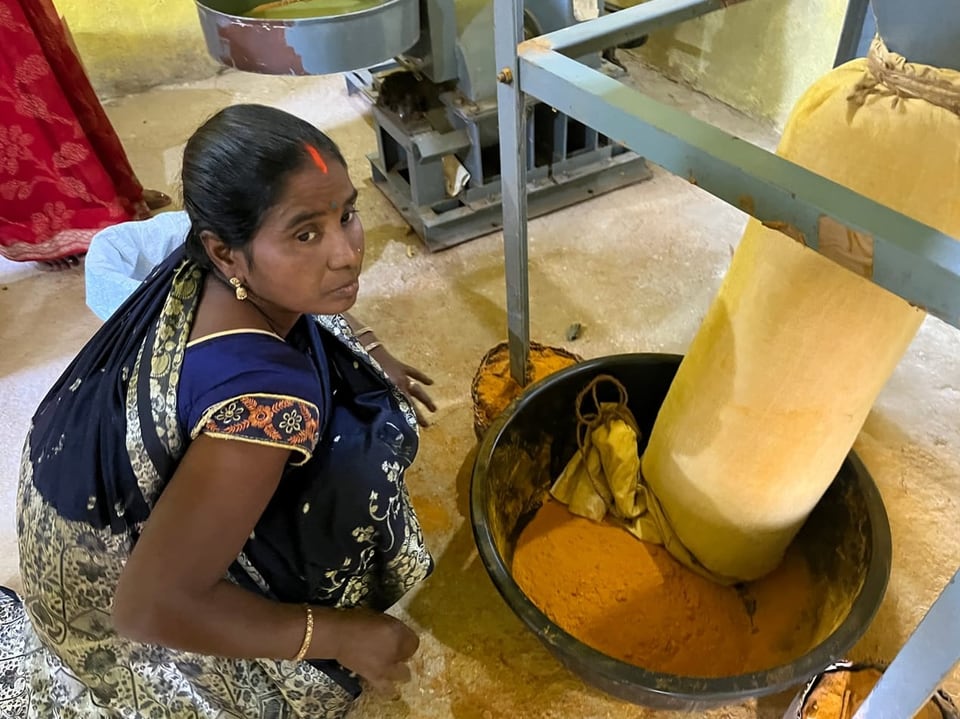 Woman kneeling in front of a turmeric mill