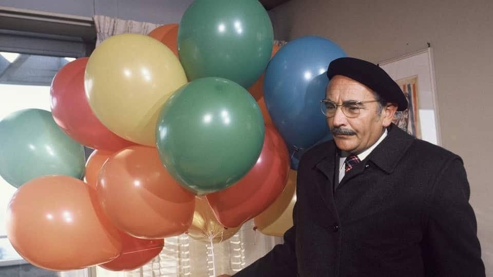 Ruedi Walter mit vielen farbigen Ballons in einem Raum.