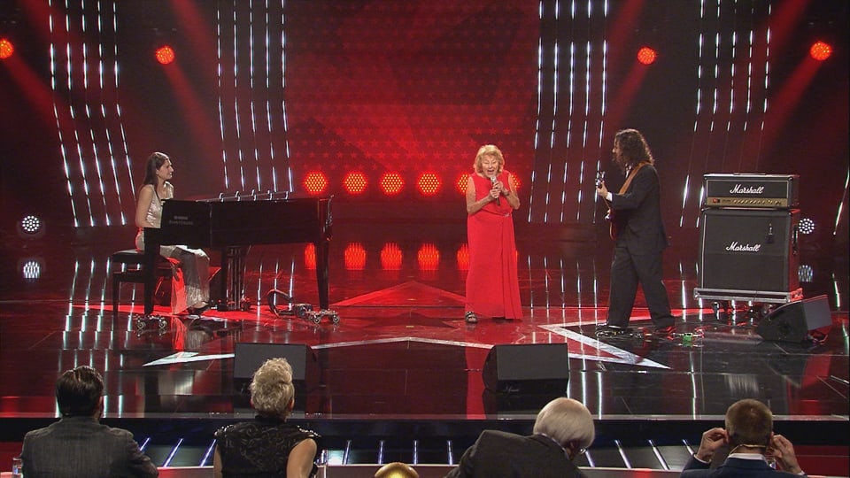 Eine Frau steht auf der Bühne mit zwei Musikern.